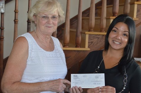 Billie Herron with check from Summer Shockley in lobby of Harrington Opera House